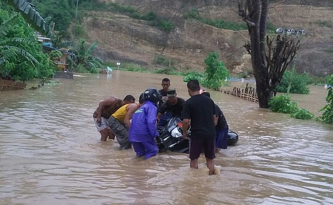 Beberapa warga berupaya menggotong sepeda motor yang terjebak di lokasi banjir, Minggu (31/1/2016). (Foto: Ist)